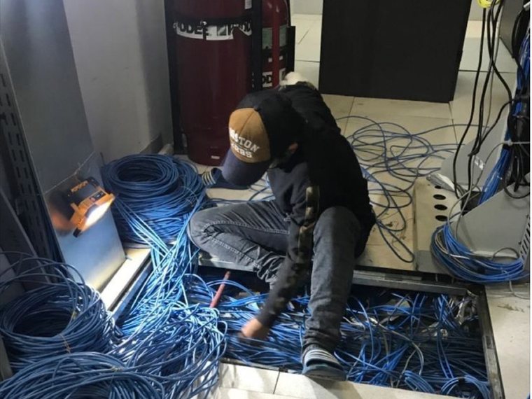 Teknisi menata instalasi kabel jaringan ruang server di Jakarta Pusat