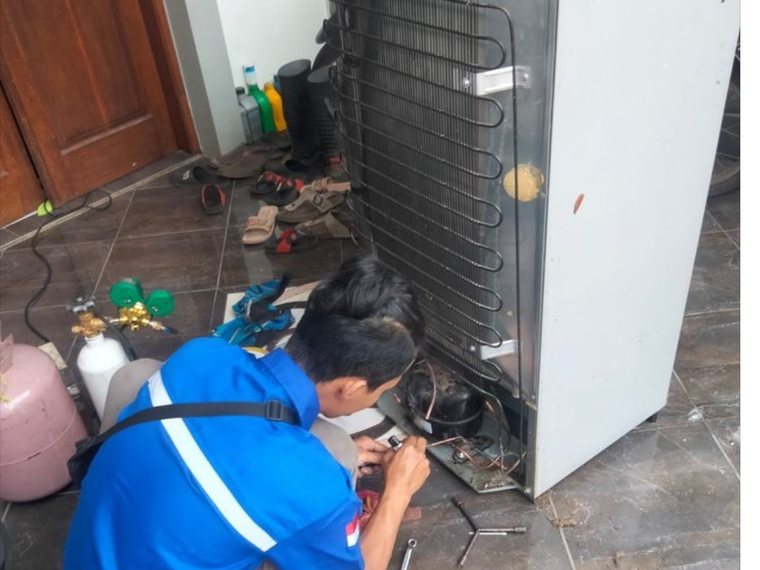 Teknisi memperbaiki kompresor kulkas di rumah pelanggan Jakarta Timur